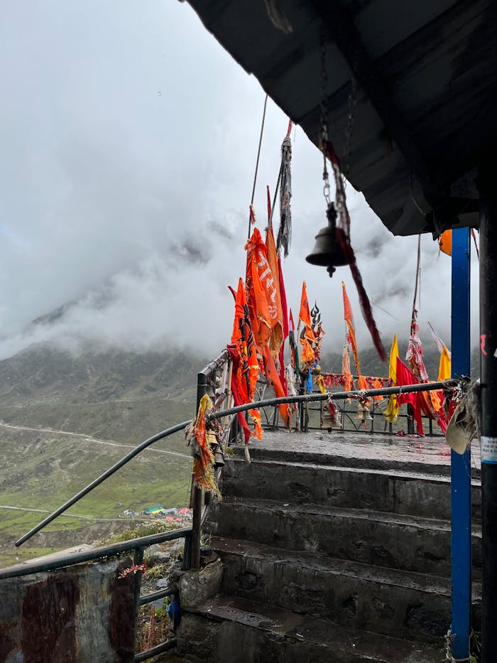 Monastery steps adorned with colorful flags amidst misty Himalayan mountains.